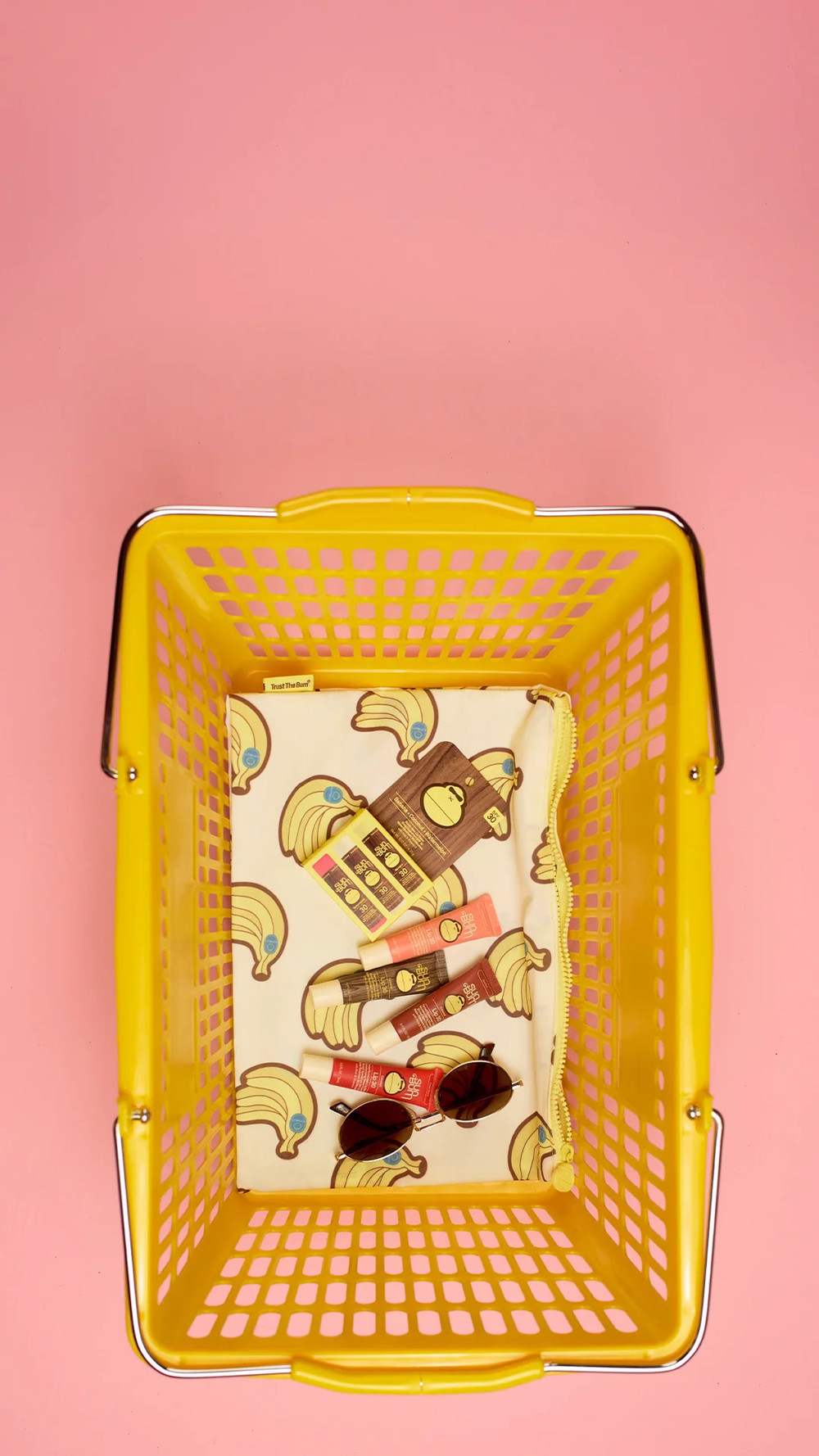 A yellow shopping basket filled with banana-patterned lining on a pink background
